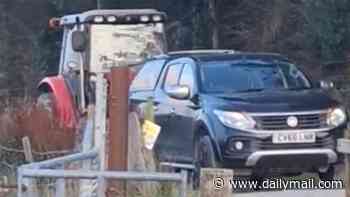 Moment feuding farmer solves his parking problem by picking up neighbour's truck with his tractor and carrying it 20 yards along lane
