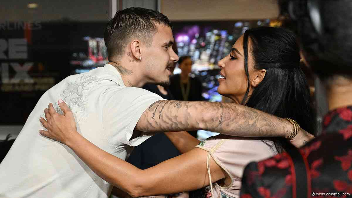 Kim Kardashian hugs Romeo Beckham in sweet moment as the pair hang out in the paddock at the Singapore Grand Prix - three years after the SKIMS mogul supported Victoria at her Paris Fashion Week show