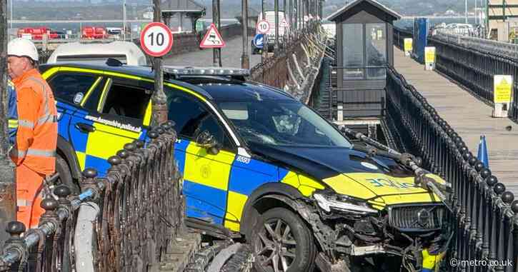 Police car dangling precariously off seaside pier in crash trapping two officers