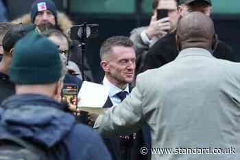 Smiling Tommy Robinson arrives at London court to face trial over claims he harassed two journalists