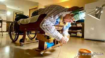Man who lost legs to MS warming heads and hearts by knitting tuques on custom-made cot