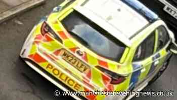 Police descend on Salford flat block with woman 'critical' in hospital